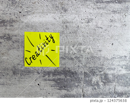 Bright yellow sticky note displaying the word Creativity with decorative elements on a textured grey background, symbolizing inspiration and the power of imaginative thinking 124375638