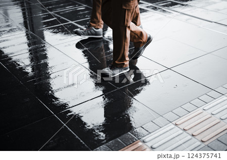 雨上がりの歩道を歩く人の足元 124375741