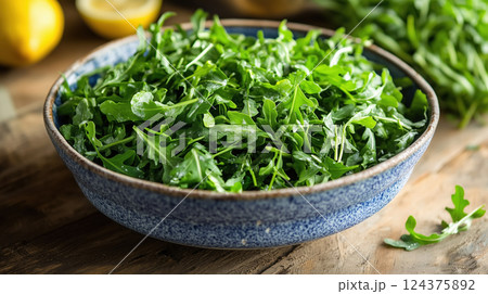 Fresh Arugula Leaves in Blue Bowl on Wooden Table Fresh Arugula Leaves in Blue Bowl on Wooden Table 124375892