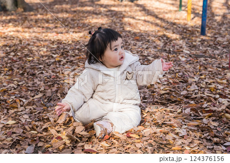 【落ち葉で敷き詰められた冬の公園で遊ぶ1歳児 座る】 【落ち葉で敷き詰められた冬の公園で遊ぶ1歳児 座る】 124376156