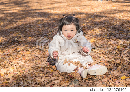 【落ち葉で敷き詰められた冬の公園で遊ぶ1歳児 座る】 【落ち葉で敷き詰められた冬の公園で遊ぶ1歳児 座る】 124376162