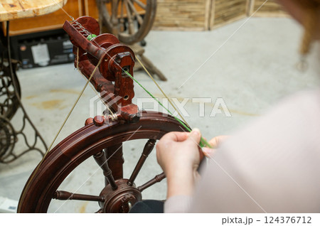 Distaff Day Female adult crafting with antique spinning wheel 124376712