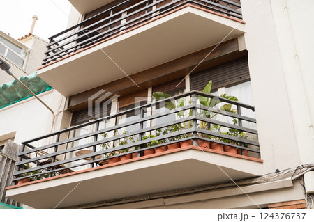 Modern apartment balcony with green plants and metal railings on residential building 124376737