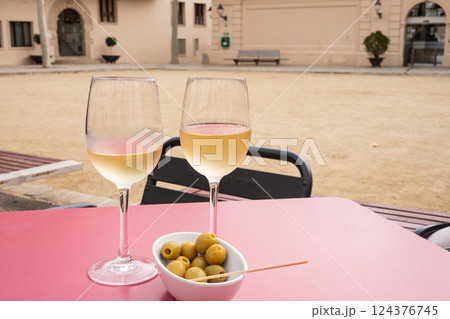 Two glasses of white wine and olives on outdoor cafe table 124376745