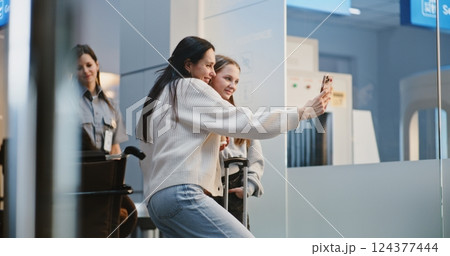 Crowded Airport Terminal: Woman Taking Selfie with Her Daughter on Phone 124377444