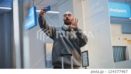 Crowded Airport Terminal: Tourist Talking on Phone by Video Call or Recording Video Content 124377467