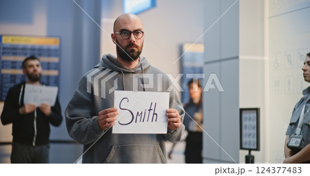 Transportation Service in Airport: Airport Greeter Holding Greeting Sign, Waiting for Passengers 124377483