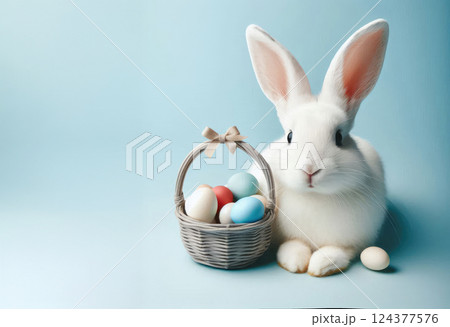 Fluffy white rabbit with basket of Easter eggs on spring meadow with green grass and flowers 124377576