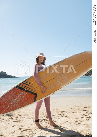 Attractive woman surfer going to surfing. Surfing of woman at beach with surfboard for freedom. Travel or sports outdoor. Vertical format. Attractive woman surfer going to surfing. Surfing of woman at beach with surfboard for freedom. Travel or sports outdoor. Vertical format. 124377838