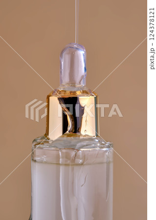 A bottle of cosmetic product with a pouring texture on top. 124378121