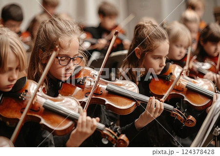 Children in orchestra playing violins, creating beautiful music 124378428