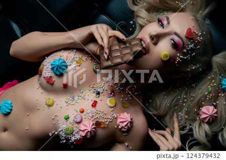 Woman with body art and candy-themed decorations enjoying chocolate treat Woman with body art and candy-themed decorations enjoying chocolate treat 124379432
