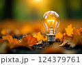 Bright light bulb illuminates a bed of autumn leaves, symbolizing ideas, inspiration, and the intersection of nature and innovation 124379761