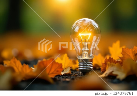 Bright light bulb illuminates a bed of autumn leaves, symbolizing ideas, inspiration, and the intersection of nature and innovation 124379761