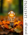 Bright light bulb illuminates a bed of autumn leaves, symbolizing ideas, inspiration, and the intersection of nature and innovation 124379762