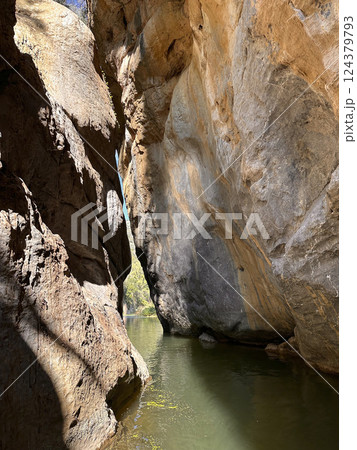 Majestic canyon with towering rock formations and tranquil water reflecting sunlight, nature exploration concept 124379793
