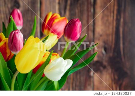 Fresh multicolored tulips on wooden background. Bouquet of spring flowers. Holiday concept. 124380027