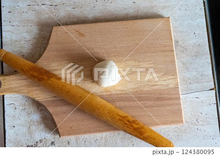 Dough ball and rolling pin resting on wooden cutting board 124380095