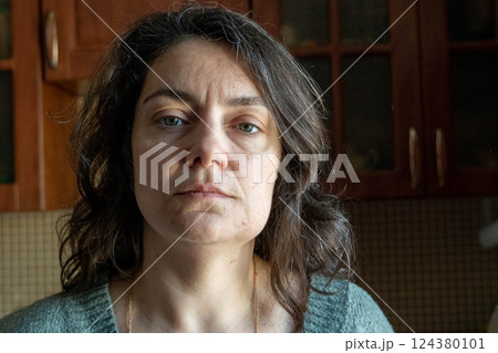 Serious brunette woman posing in kitchen with cabinets in background 124380101