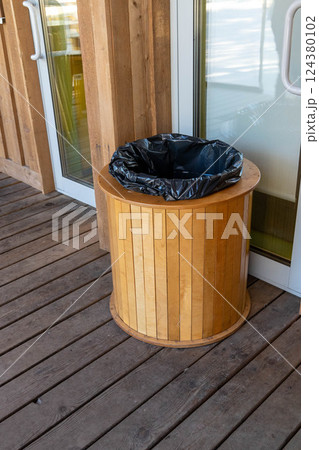 Round wooden trash can with black plastic bag outdoors Round wooden trash can with black plastic bag outdoors 124380102