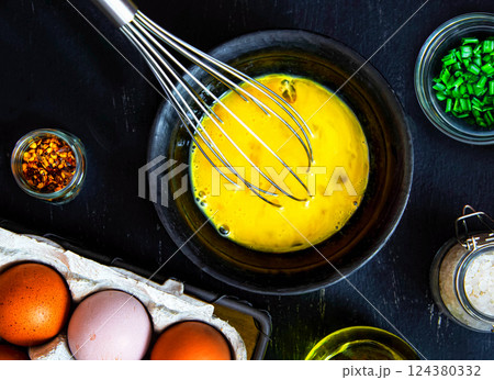 Beat eggs in a bowl, and ingredients for making an omelette with green onions Beat eggs in a bowl, and ingredients for making an omelette with green onions 124380332