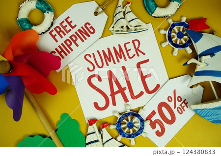 SUMMER SALE 50% OFF text on paper card with marine items decorative top view on yellow background SUMMER SALE 50% OFF text on paper card with marine items decorative top view on yellow background 124380833
