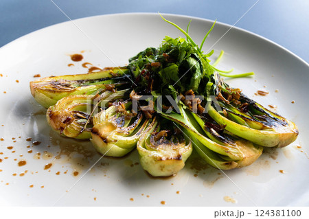 Grilled bok choy showcases vibrant green colors, topped with fresh herbs and sauce, ready to serve. Grilled bok choy showcases vibrant green colors, topped with fresh herbs and sauce, ready to serve. 124381100