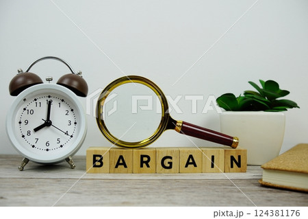 Magnifying glass and alarm clock with wooden blocks alphabet letters BARGAIN text message on wooden background Magnifying glass and alarm clock with wooden blocks alphabet letters BARGAIN text message on wooden background 124381176