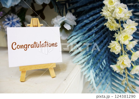 Congratulations text write on paper card with wooden easel and flowers decoration on wooden background Congratulations text write on paper card with wooden easel and flowers decoration on wooden background 124381290