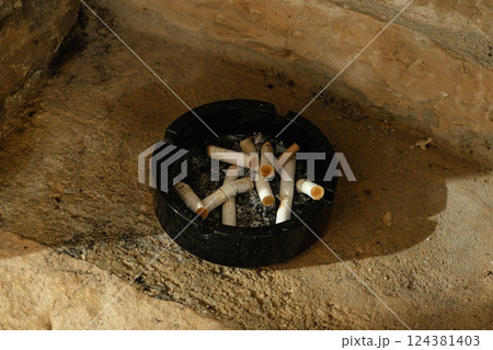 Black Ashtray with Cigarette Butts on Stone Black Ashtray with Cigarette Butts on Stone 124381403