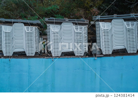 Stacked White Plastic Lounge Chairs in Storage at the End of the Season on the Mediterranean Coast Stacked White Plastic Lounge Chairs in Storage at the End of the Season on the Mediterranean Coast 124381414