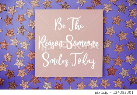 Be The Reason Someone Smiles Today text motivational and inspiration quote on paper card with star glitter decoration flat lay on purple background Be The Reason Someone Smiles Today text motivational and inspiration quote on paper card with star glitter decoration flat lay on purple background 124382301