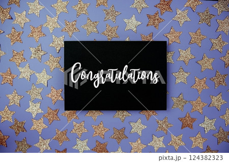 Congratulations text on paper card with star glitter decoration flat lay on purple background Congratulations text on paper card with star glitter decoration flat lay on purple background 124382323