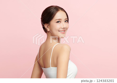 A beautiful young Asian woman with clean, fresh skin against a pink background. Skincare, facial treatment, cosmetology, beauty, and spa. An elegant portrait of an Asian woman. 124383201