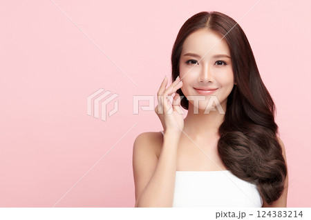 A beautiful young Asian woman with clean, fresh skin against a pink background. Skincare, facial treatment, cosmetology, beauty, and spa. An elegant portrait of an Asian woman. 124383214