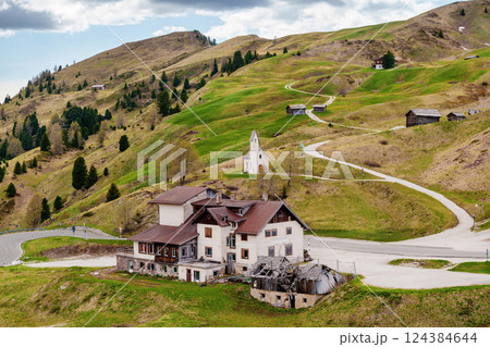 Scenic mountain landscape with country house and winding road leading to a chapel near Valley of Funes at Dolomites, Italy 124384644