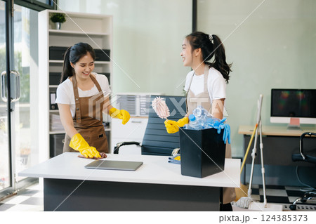 Two professional cleaners tidying a stylish space with a smile. Experience efficient and friendly house cleaning 124385373