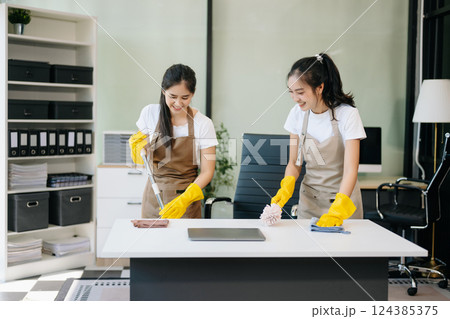 Two professional cleaners tidying a stylish space with a smile. Experience efficient and friendly house cleaning Two professional cleaners tidying a stylish space with a smile. Experience efficient and friendly house cleaning 124385375