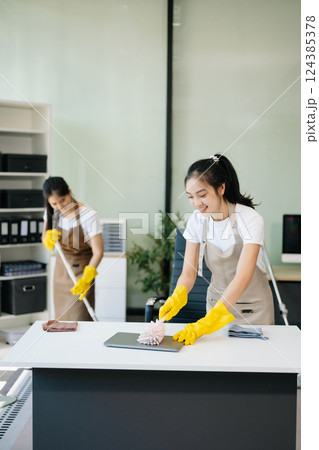Two professional cleaners tidying a stylish space with a smile. Experience efficient and friendly house cleaning 124385378