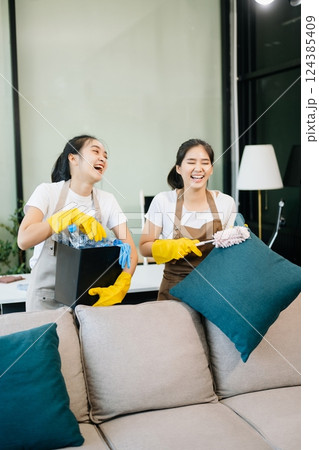 Two professional cleaners tidying a stylish space with a smile. Experience efficient and friendly house cleaning 124385409