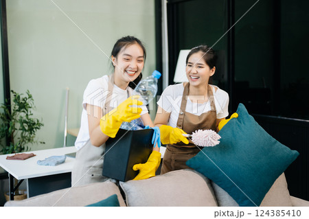 Two professional cleaners tidying a stylish space with a smile. Experience efficient and friendly house cleaning 124385410