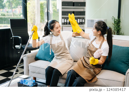 Two professional cleaners tidying a stylish space with a smile. Experience efficient and friendly house cleaning Two professional cleaners tidying a stylish space with a smile. Experience efficient and friendly house cleaning 124385417