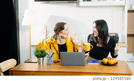 Modern couple collaborating over coffee in a cozy kitchen setting with a laptop, notebook, and breakfast. Modern couple collaborating over coffee in a cozy kitchen setting with a laptop, notebook, and breakfast. 124385580