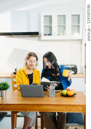 Modern couple collaborating over coffee in a cozy kitchen setting with a laptop, notebook, and breakfast. 124385586