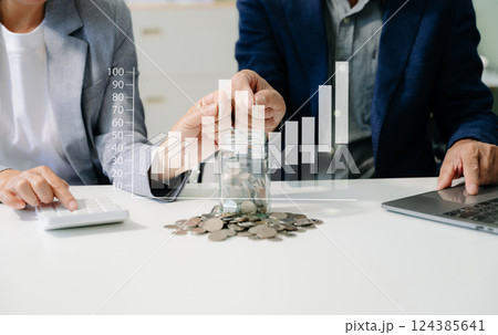 saving money with hand putting coins in jug glass and calculator to calculate budget concept 124385641