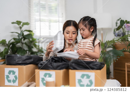 Environmental Awareness and Educational Moments. A mother and daughter engage in recycling while discovering the importance of responsible disposal. Environmental Awareness and Educational Moments. A mother and daughter engage in recycling while discovering the importance of responsible disposal. 124385812
