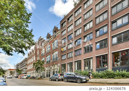 A picturesque street scene featuring modern buildings alongside traditional architecture, complemented by lush greenery and a clear sky. 124386676