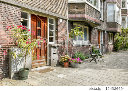 A welcoming entrance featuring a blend of vibrant plants and a cozy seating area, set within a stylish brick building. 124386694