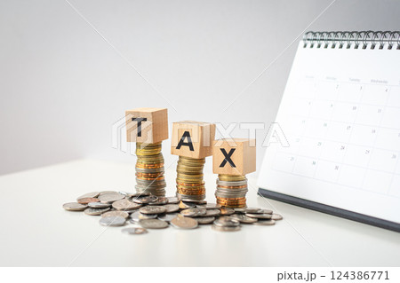 Tax word on wood blocks on top of coins with calendar at the background. 124386771