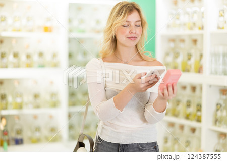 Young woman scanning qr code for eau de toilette 124387555